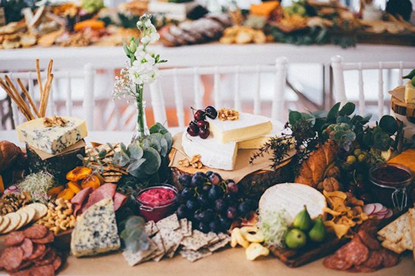 large table with various meats, cheeses, breads, and fruit