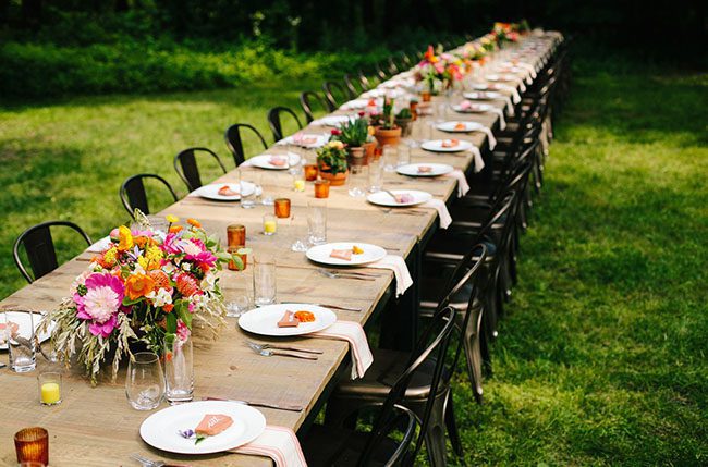 Long table outdoors with lots of flowers and cacti set for a wedding