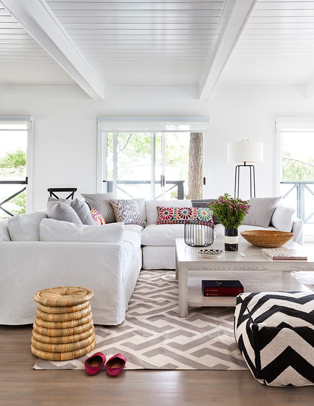 white livingroom with wicker stool and bright patterned cushions