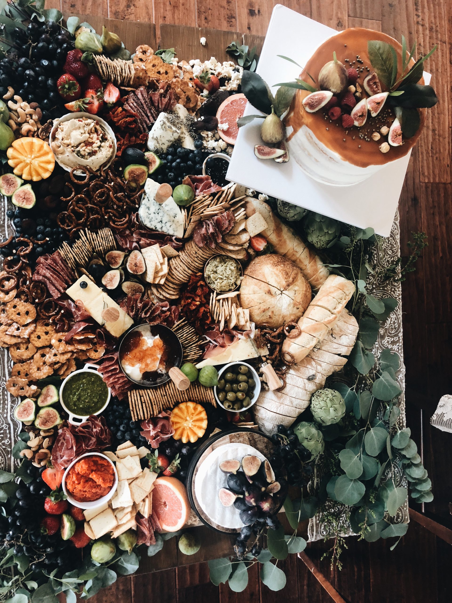 large table filled with various meat, cheese, breads, and fruit