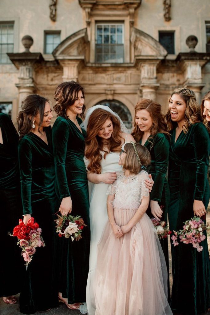 bride with red hair surrounded by bridesmaids in emerald green crushed velvet long dresses