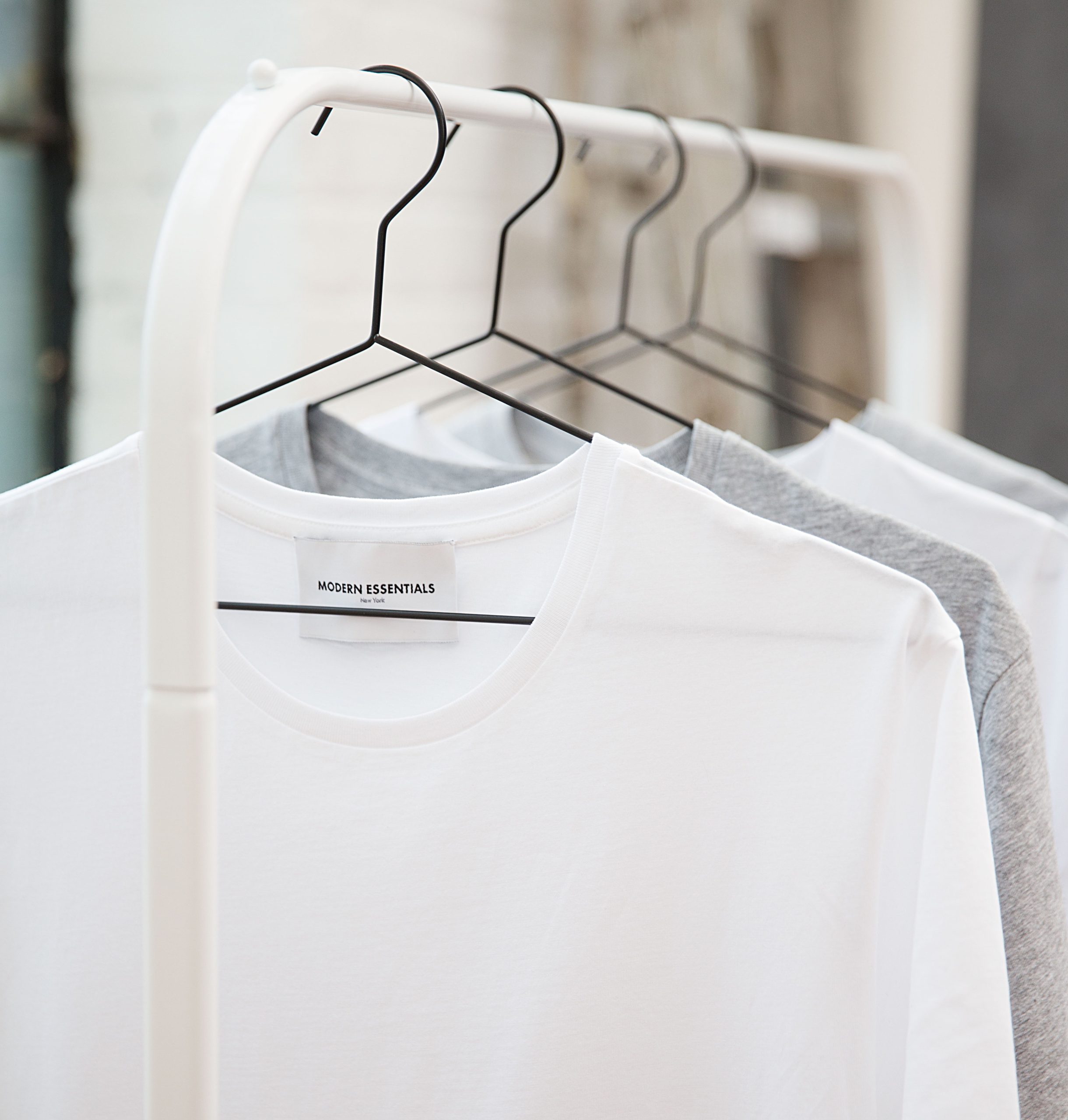 clothing rack with a few white and grey t-shirts on it
