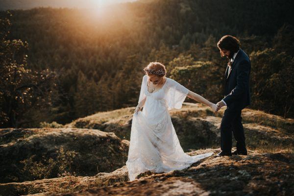 Bride and groom holding hands and walking on a mountain at sunset