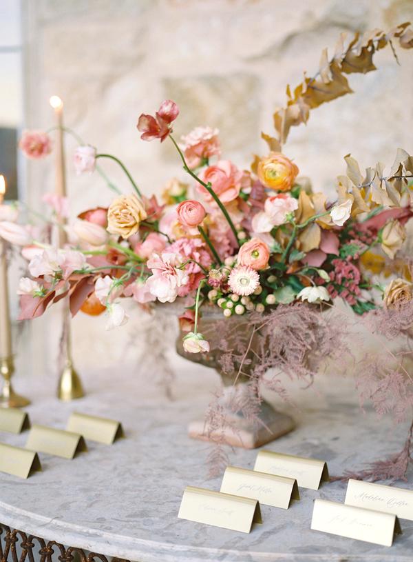Extravagant table setting with a big vase of pink and orange flowers