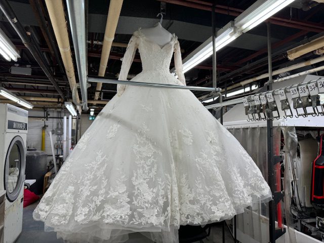 front of lace ball gown wedding dress hanging from a hanger